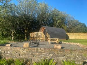 a circular cabin with a fire pit and a fence at The Fells - Campsie Luxury Pods with hot tub in Glasgow