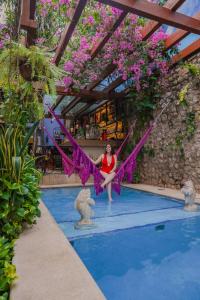 a woman in a red dress is standing in a pool at Le Muuch Hotel Boutique in Valladolid