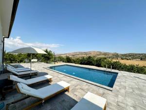 a swimming pool with lounge chairs and an umbrella at Villa Cirasa in Aragona