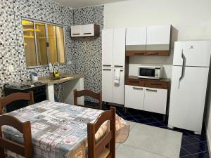 a kitchen with a table and a white refrigerator at Studio Cotia Centro próximo ao Animalia Park CT do São Paulo Thermas da Mata Shopping Central Park in Cotia