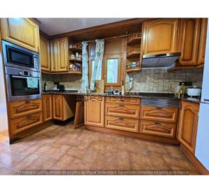 カステルデフェルスにあるVilla avec piscine quartier résidentielの木製のキャビネットとコンロ付きオーブンを備えたキッチン