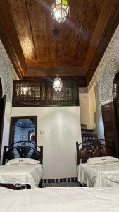 una camera con 2 letti e un soffitto in legno di Dar El Arfaoui a Fes