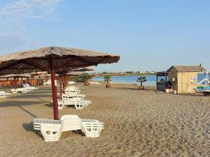 een groep stoelen en een parasol op een strand bij APARTMAN SUNSIDE2 NIN in Nin