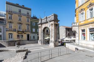 a stone arch in a city with buildings at Porta Aurea sunny studio in Pula