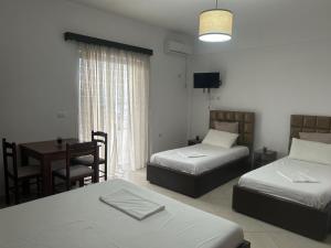 a room with two beds and a table with a desk at Ahmeti Rooms in Ksamil