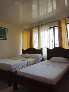 2 camas en una habitación con ventanas en Hotel Unión, en Villavicencio