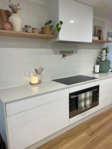 Una cocina con gabinetes blancos y un horno de estufa. en Holiday on Hooper, en Port Moonta