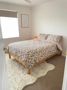 Un dormitorio con una cama con edredón floral y una ventana. en Holiday on Hooper, en Port Moonta