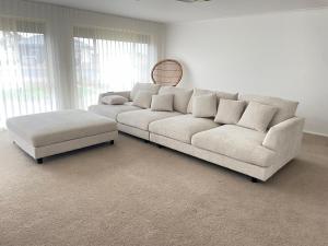 sala de estar con sofá blanco y reposapiés en Holiday on Hooper, en Port Moonta