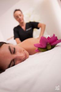 a woman laying on a bed with a flower on it at Chambres d'Hotes Spa Château d'Omiécourt in Omiécourt