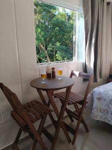 una mesa con dos vasos y dos sillas frente a una ventana en Nosso Bosque Hospedaria, en Penha