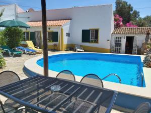 een zwembad met een tafel en stoelen en een huis bij Casa Delfim - Casa Verde in Alte