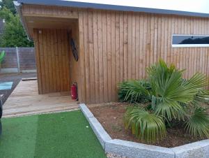 a building with a wooden door and some plants at Chalet container 60m2 in La Neuville-du-Bosc