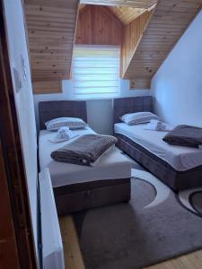 two beds in a small room with wooden ceilings at Vikendica u srcu Bjelasnice in Trnovo
