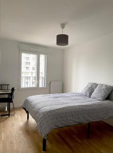 Un dormitorio blanco con una cama y una ventana. en 3 pièces tout neuf de haut standing à 10mn de Paris avec terrasse vue Sacré Coeur, en Asnières-sur-Seine