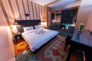 a bedroom with a large bed with white sheets at Hotel Akouas in Meknès