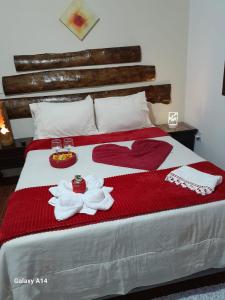 a bed with red and white blankets and towels on it at Casa da Lu in Macaé