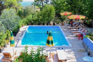 a person swimming in a swimming pool with umbrellas and chairs at Gini Palace - Shengjin in Shëngjin