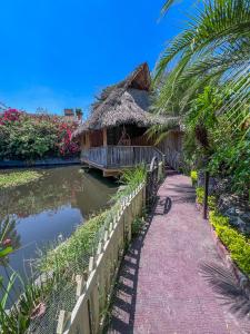 a house with a thatched roof next to a canal at Finca las Isabeles in Xochitepec