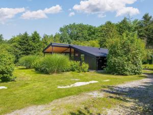 un edificio negro con un techo negro en un campo en 6 person holiday home in Glesborg-By Traum, en Glesborg