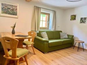 a living room with a green couch and a table at Ferienwohnungen Angerer Kederlehen in Berchtesgaden +43 photos