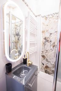 een badkamer met een wastafel en een spiegel bij Appartement Royal carré d'or de Paris 17 eme in Parijs