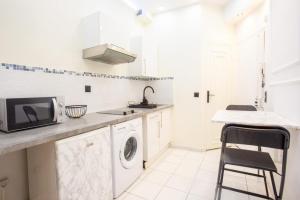een witte keuken met een wastafel en een wasmachine bij Appartement Royal carré d'or de Paris 17 eme in Parijs