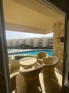 ein Balkon mit Tisch und Stühlen und ein Pool in der Unterkunft Blumar Eldome in Ain Suchna