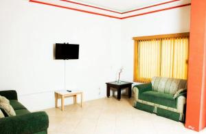 a living room with two green couches and a tv at Casa Punta Yatareni in Yelateni