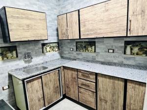 a kitchen with wooden cabinets and a sink at شقة فندقية vip برج رئيسي شارع الغشام مع موقف المنصورة in Manshīyat as Sādāt +8 photos