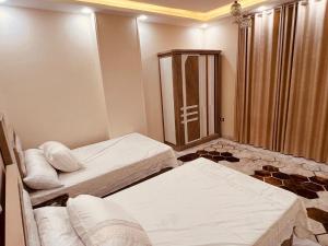 a hotel room with two beds and a shower at شقة فندقية vip برج رئيسي شارع الغشام مع موقف المنصورة in Manshīyat as Sādāt