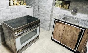a kitchen with a stove and a sink at شقة فندقية vip برج رئيسي شارع الغشام مع موقف المنصورة in Manshīyat as Sādāt