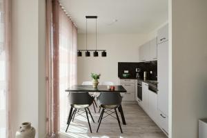 a kitchen with a black table and two chairs at Apartment B14 mit Südbalkon & Nutzung der Wellness- & Aktivbereiche im "Pine Hill Resort" in Zirchow