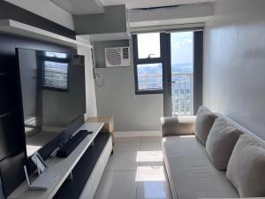 Una sala de estar con un sofá y un televisor. en 1 bedrm condo, Tower 2, Hor 101, en Cebú