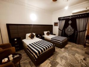 a hotel room with two beds and a couch at Shelton House in Karachi