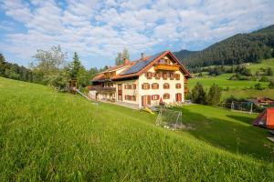 una grande casa su una collina con un campo verde di Gästehaus Schlegel a Gunzesried