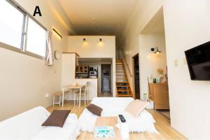 a living room with two white couches and a kitchen at MOTOBU Hills DUPLEX in Motobu