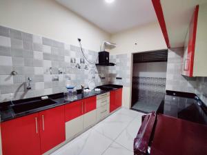 a kitchen with red cabinets and a red sink at Urban comfort- Home stay in Mysore