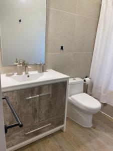 Un baño con lavabo, inodoro y espejo. en Pucon Villarrica Aldea Molco, en Molco