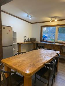 cocina con mesa de madera con sillas y nevera en Pucon Villarrica Aldea Molco, en Molco