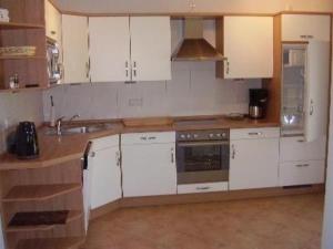 une cuisine avec des armoires blanches et un évier dans l'établissement Bungalow Meeresbrise mit WLAN, à Butjadingen