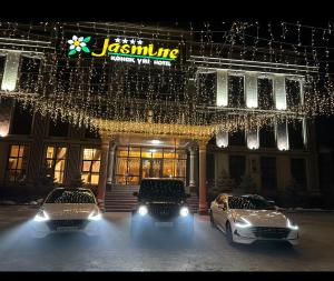 two cars parked in front of a building with lights at Jasmine in Taraz
