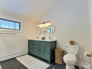 a bathroom with a toilet and a sink and mirrors at Beartopia- Hot Tub, Views, 2 Primary Suites! in Killington +45 photos