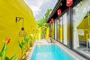 une maison jaune avec une piscine à côté d'un immeuble dans l'établissement Rosie Countryside villa- 1BR retreat, à Hiếu Nhơn 2 autres photos