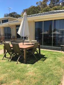 a table and chairs with an umbrella on the grass at Coastal Blue in Seacliff