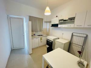 a small kitchen with white cabinets and a table at akrata siesta in Akrata +51 photos