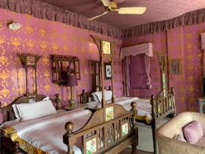 a bedroom with two beds and purple walls at Bhairon villas in Bikaner