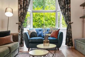 a living room with a blue couch and a large window at 3 bed city centre, FREE parking, Contractors, Long Stays in Doncaster