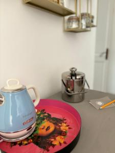 a tea kettle on a pink plate on a counter at L'Intemporel in Saint-Cyr-sur-Mer