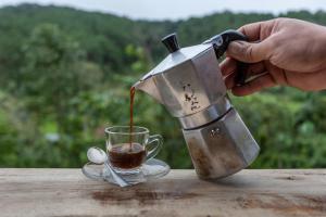 a person pouring coffee into a cup on a table at Palacoffeehouse ปางอุ๋ง in Ban Huai Makhuea Som